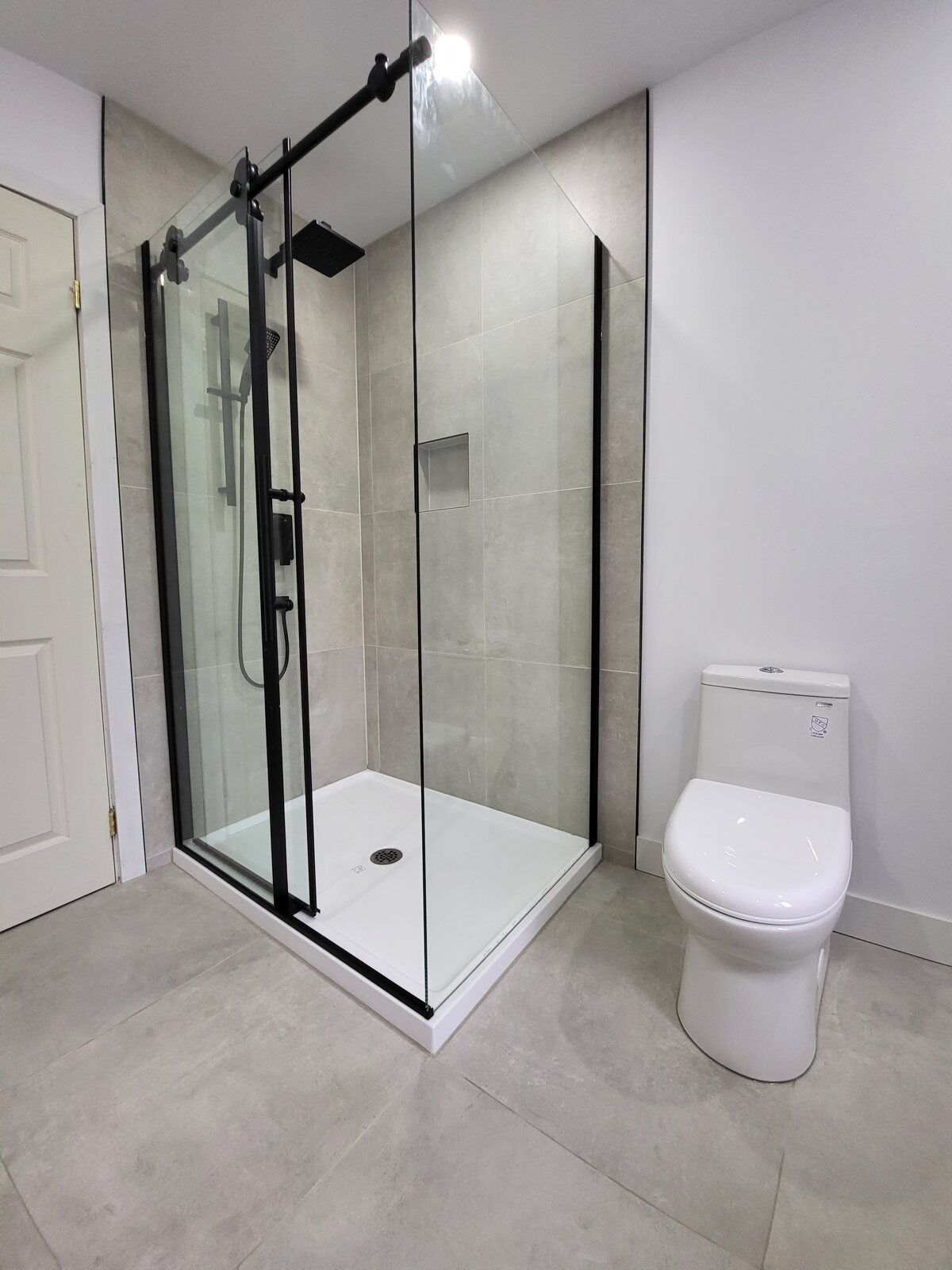 Douche vitrée avec grande céramique grise et robinetterie noire