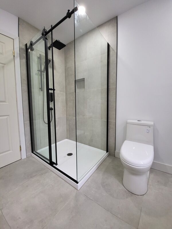 Douche vitrée avec grande céramique grise et robinetterie noire