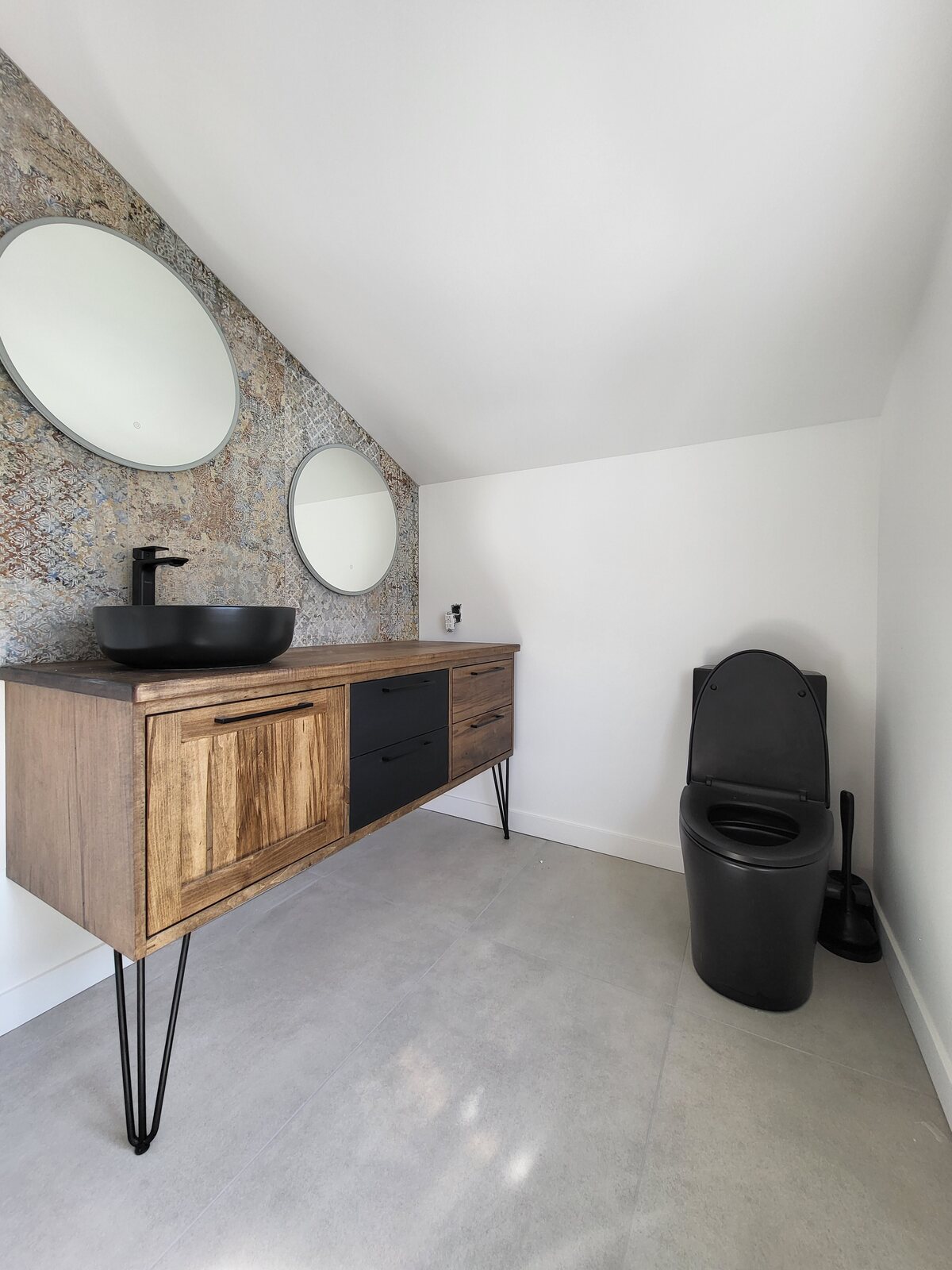 Salle de bain avec vanité en bois, lavabo noir et mur décoratif