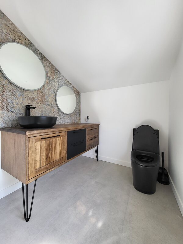 Vanité en bois avec lavabo noir, miroirs ronds et dosseret décoratif