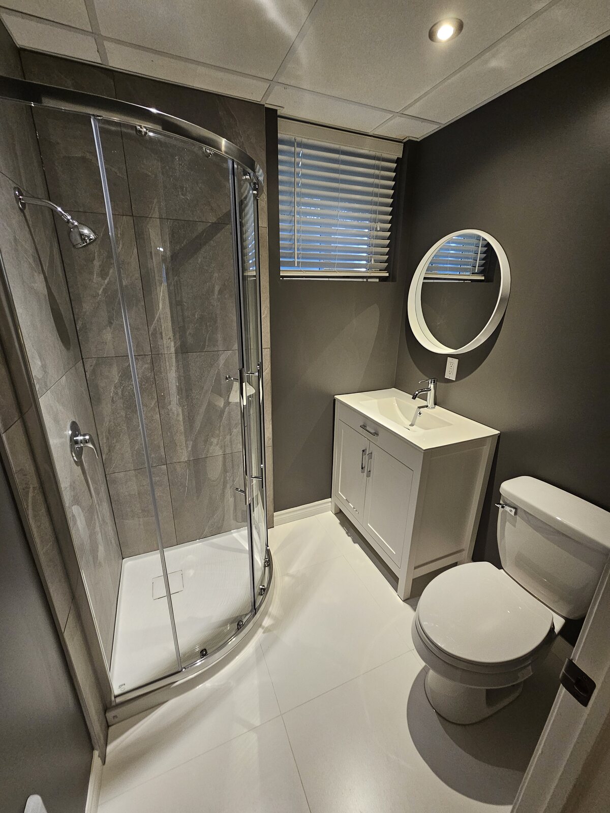 Salle de bain avec meuble-lavabo en bois, douche vitrée et porte coulissante