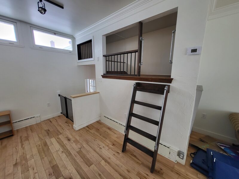 Sous-sol avec escalier, garde-corps et plancher de bois