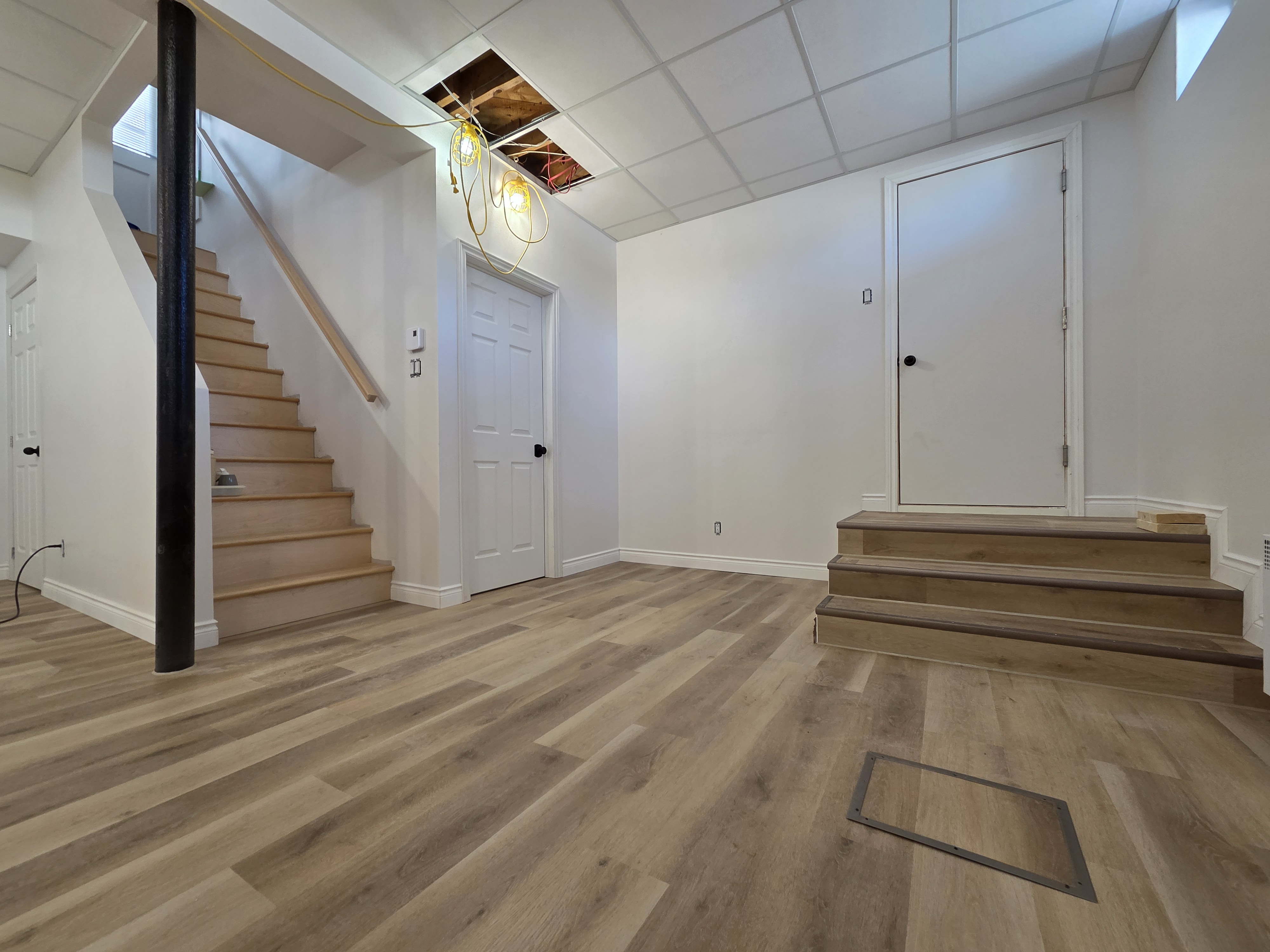 Sous-sol aménagé avec escalier, portes et plancher de bois