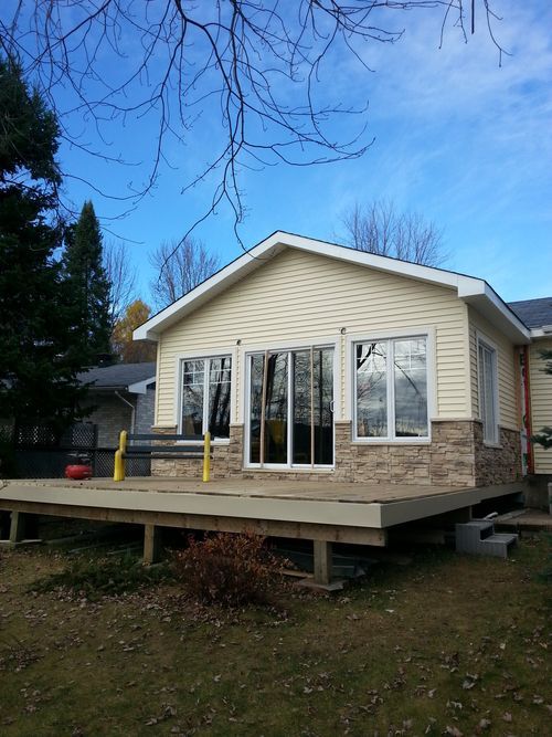 Agrandissement à l’arrière d’une maison avec terrasse de bois